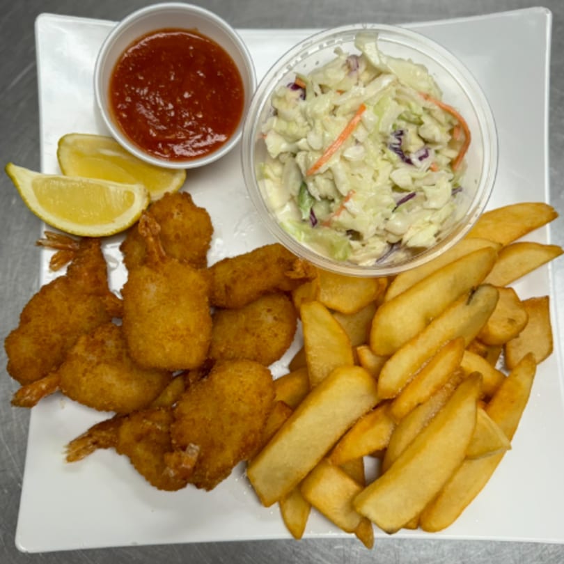 Fried shrimp, steak fries, coleslaw, cocktail sauce, and lemon wedges on a white plate.